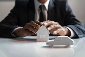 Professional Businessman in Suit Protecting Model House and Car Representing Insurance and Security photo