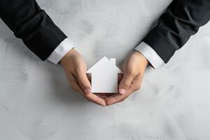 Businessman in Suit Protecting a House Model with His Hands on a Light Background, Symbolizing Real Estate and Security photo