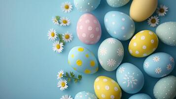 Easter pastel colored eggs with spring flowers on blue paper background, copy space, top view photo