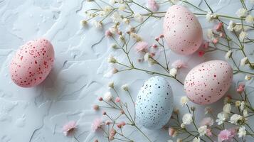 Easter colored eggs with spring flowers on pastel blue background, copy space, top view photo