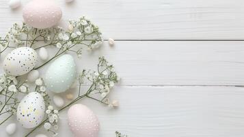 Easter pastel eggs with spring flowers on pastel wooden white background with copy space, top view photo