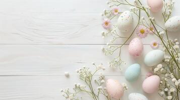 Easter pastel eggs with spring flowers on pastel wooden white background with copy space, top view photo