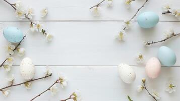 Easter pastel eggs with spring flowers on pastel wooden white background with copy space, top view photo