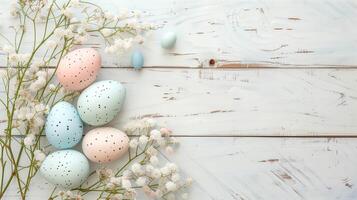 Easter pastel eggs with spring flowers on pastel wooden white background with copy space, top view photo