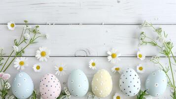Easter pastel eggs with spring flowers on pastel wooden white background with copy space, top view photo