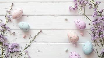Easter pastel colored eggs with spring flowers on blue paper background, copy space, top view photo