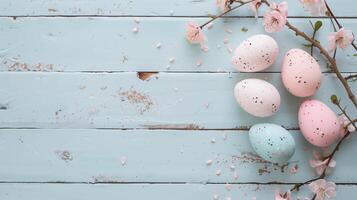 Easter pastel eggs with spring flowers on pastel wooden blue background with copy space, top view photo