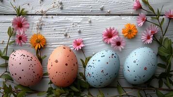 Easter pastel eggs with spring flowers on pastel wooden white background with copy space, top view photo