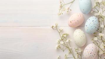 Easter pastel eggs with spring flowers on pastel wooden white background with copy space, top view photo