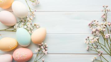 Easter pastel eggs with spring flowers on pastel wooden white background with copy space, top view photo