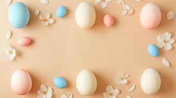 Easter pastel colored eggs with spring flowers on beige paper background, copy space, top view photo