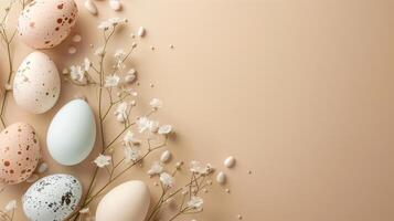 Easter pastel colored eggs with spring flowers on beige paper background, copy space, top view photo