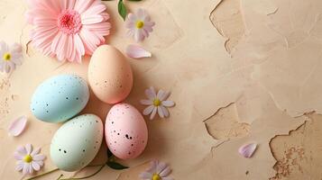 Easter pastel colored eggs with spring flowers on beige paper background, copy space, top view photo