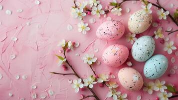 Easter pastel colored eggs with spring flowers on pink paper background, copy space, top view photo
