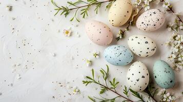 Easter pastel colored eggs with spring flowers on white background, copy space, top view photo
