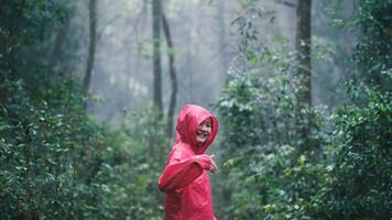 Generated A woman wearing a red raincoat smiles with joy as she enjoys the fresh air and natural beauty of a lush forest on a misty day.image photo