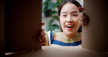 Selective focus, Happy young woman open a cardboard box to look at the items she moved from old home. Moving house and lifestyle concept. photo