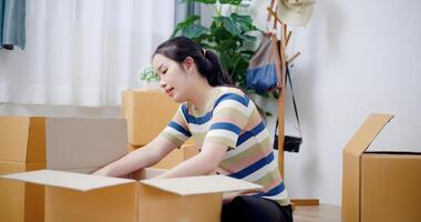 Portrait of Happy young woman packing her things into a cardboard box in preparation for moving to a new house. Moving and lifestyle concepts. photo