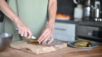 Woman slicing Salted pickles with knife from jar can, Cucumbers preservations, conservation. Salted pickled cucumbers in a wooden table. Preparing the salad video