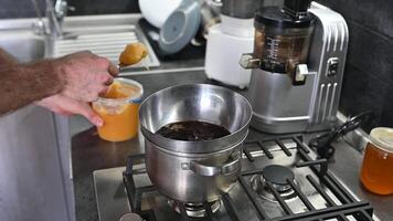A man makes homemade chocolate. Melts cocoa butter and cocoa beans in a water bath, adding honey. The process of making healthy sugar-free and gluten-free candies at home video