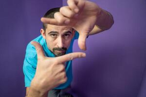 Man doing frame using hands and fingers, isolated over purple background photo