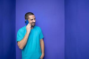 Happy young man talking with mobile phone on color background photo