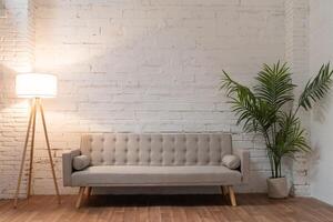 White brick wall with sofa pot with plant and light. Background photo with copy space for text.