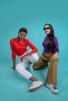 Two fashion models with sunglasses posing with attitude on a blue studio background photo