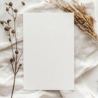 Blank paper with dried flowers on soft fabric background, perfect for invitations or decorative notes in natural light photo