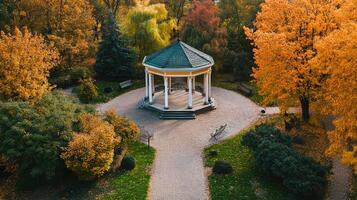 Elegant gazebo in a tranquil park surrounded by vibrant autumn foliage during a sunny afternoon photo