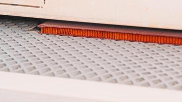 Close-up view of the conveyor-based production process for the creation of orange-colored waterproof panels, which are used to construct walls and ceilings. Slow motion video