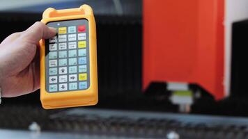Close-up shot of the hand of an operator initiating a metal laser-cutting machine at a remote-controlled facility. Slow motion video