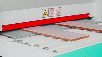 Close-up view of two flat panels, which are used in the manufacturing of furniture, being loaded into industrial machinery for the purpose of pressing and processing. Slow motion video