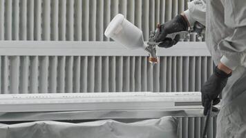 Close-up of the application of white paint from a spray gun on a part in an industrial setting. Close up. Slow motion. video