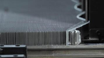 Macro photography of a metallic mesh, which has been stretched using industrial machinery to achieve the desired shape. Close up. Slow motion video