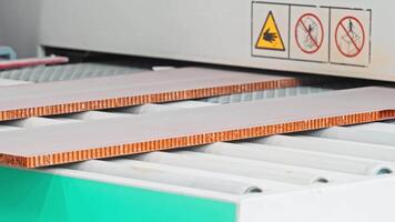 Close-up shot of the production process of panels made from composite materials, as they appear directly on the assembly line. Slow motion video