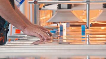 Worker operates a conveyor belt, directing large sheets of metal and loading them into a machine for assembly. Close up. video