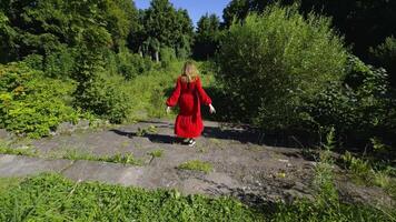 A woman in a striking red dress runs down ancient stone steps, surrounded by dense greenery in an abandoned park. The back view captures her swift movement with a wide-angle shot, highlighting the video