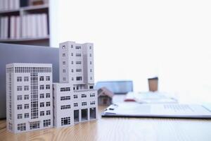 Mock up of building and documents placed on the desk of the agent in the real estate office to prepare for the customers who will come to see the property before deciding to buy the real estate. photo