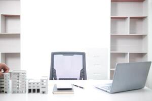 Mock up of building and documents placed on the desk of the agent in the real estate office to prepare for the customers who will come to see the property before deciding to buy the real estate. photo