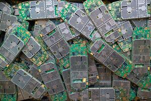 pile of electronic waste on factory floor is circuit board of mobile phone waiting to be processed extract gold to separate precious metal from electronic waste. extracting precious metal from e-waste photo