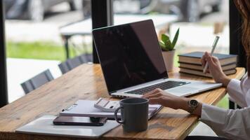 young businesswoman is reviewing results of corporate network via laptops and the Internet in order to prepare documents for meetings to give investors confidence in doing business. photo