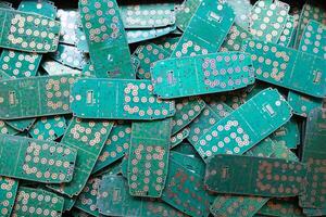 pile of electronic waste on factory floor is circuit board of mobile phone waiting to be processed extract gold to separate precious metal from electronic waste. extracting precious metal from e-waste photo