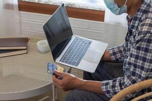 A young man is using a credit card to pay for online shopping during breaks to get the products he wants from online stores without having to travel by himself and at the convenience of you photo