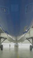 Airplane in hangar, rear view of aircraft and light from windows. Large passenger aircraft in a hangar on service maintenance video