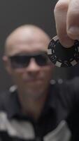 Man drops chip on poker table. Action. Bandit with glasses drops chip on pile of chips on poker table. Gambling and crime video