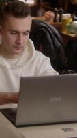 Working environment. Stock footage. A young man sitting in a cafe and working at a laptop while talking on the phone. video