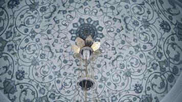 Bottom view of the white ceiling with blue ornamental pattern. Scene. Hanging chandelier inside the building. video
