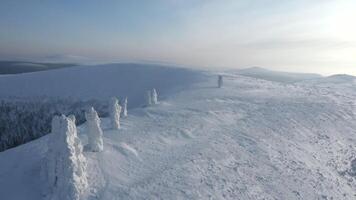 Landscape in sub-zero temperatures from above. Clip.Snowy empty mountains with frozen hills and trees are visible against a bright sky. video