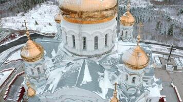 Aerial view of a white church with golden domes on a winter day. Clip. Giant church building on a countryside background. video